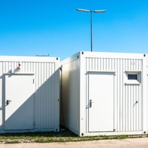 white shipping containers modified with doors and windows with a blue sky background