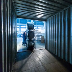 workers pushing cargo on a cart into an open shipping container