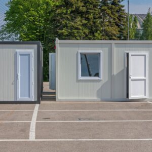 shipping containers modified to have regular doors and windows sitting in a parking lot