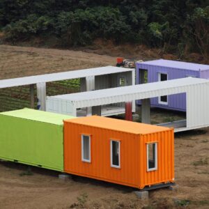 several colorful shipping containers sitting in a dirt field