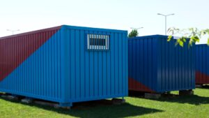 two blue shipping containers sitting on concrete blocks surrounded by grass