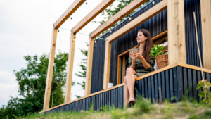 woman sits under a pergola outside of a modern structure