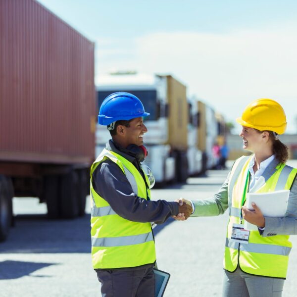 Man and woman shaking hands in front of containers