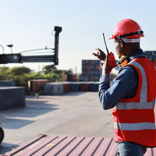 Man on walkie talkie near shipping containers