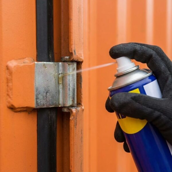 a person applying lubricant to a container's door hinge