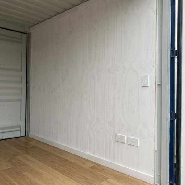 Interior of a shipping container with finished walls, outlets, and a light switch